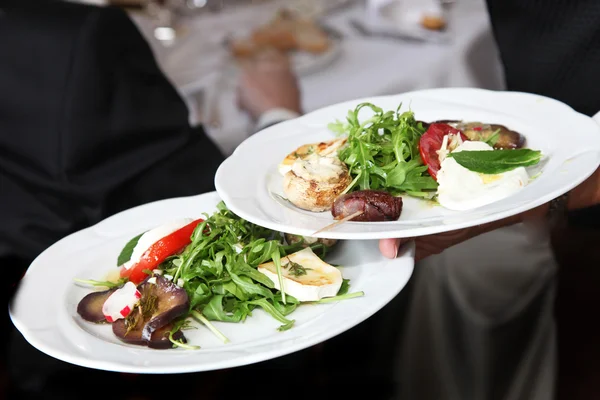 Waiter carrying plates of starters — Stock Photo, Image
