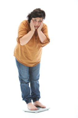 Middle-aged woman stands on a scale and is shocked clipart