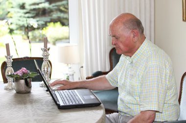 Senior man working on a laptop clipart