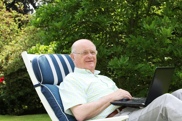 Emeryt korzysta z laptopa w ogrodzie — Zdjęcie stockowe