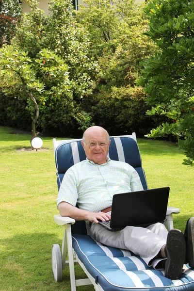 Senior man using laptop in garden — Stock Photo, Image