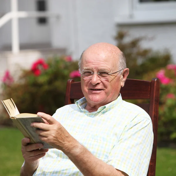 Счастливый пенсионер отдыхает с книгой — стоковое фото