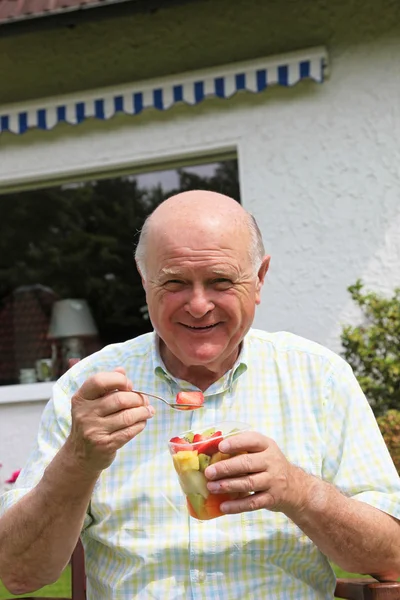 Homem idoso comendo salada de frutas frescas — Fotografia de Stock