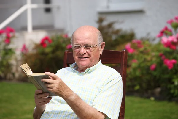 Elderly man reading a book in sunshine — Stock Photo, Image