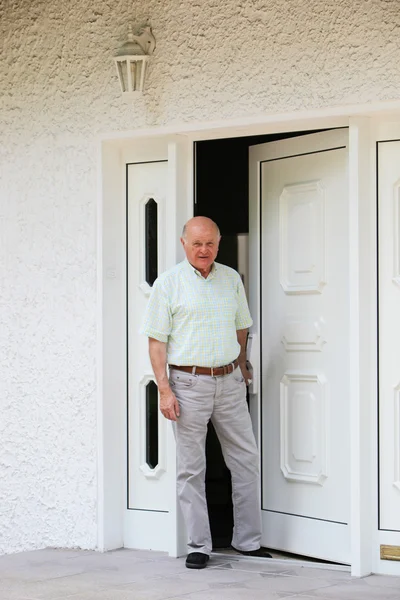 Пенсионер в дверях своего дома — стоковое фото