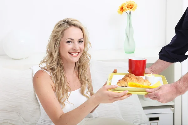 Ung kvinna som behandlas för att frukost på sängen — Stockfoto