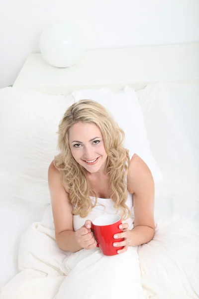 Jeune femme buvant du café au lit — Photo