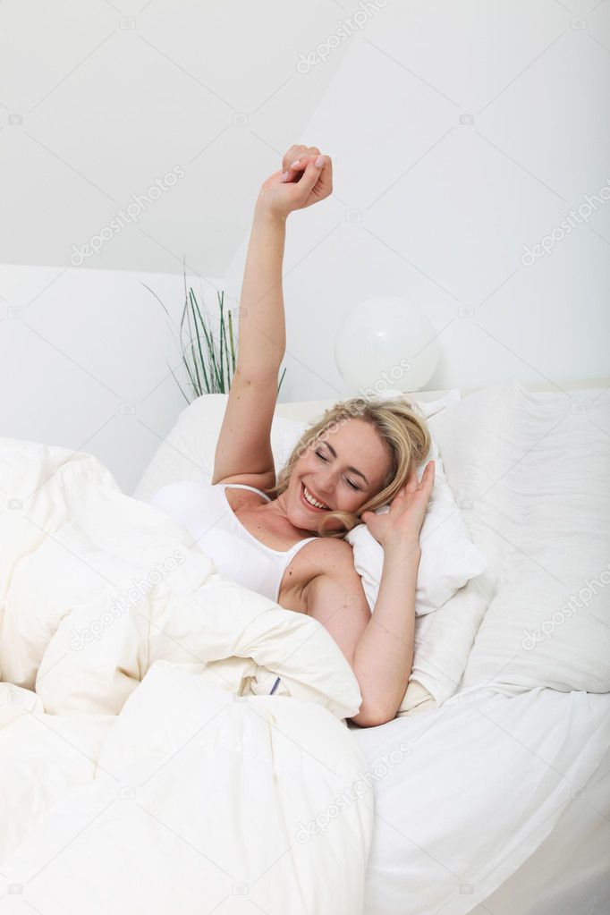 Woman stretching against her pillows