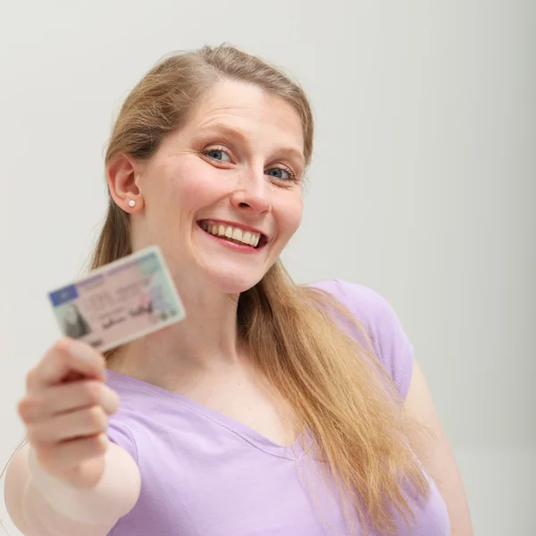 Lachende blonde vrouw toont haar identiteitskaart — Stockfoto
