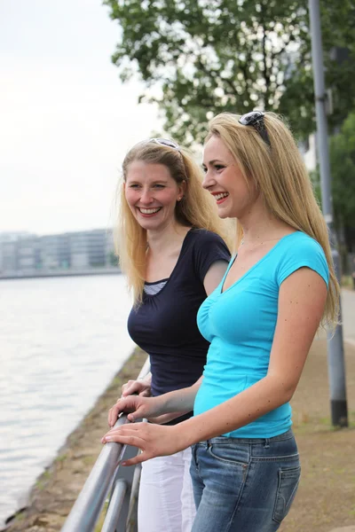 Lächelnde Freunde, die entlang eines Flusses reden — Stockfoto