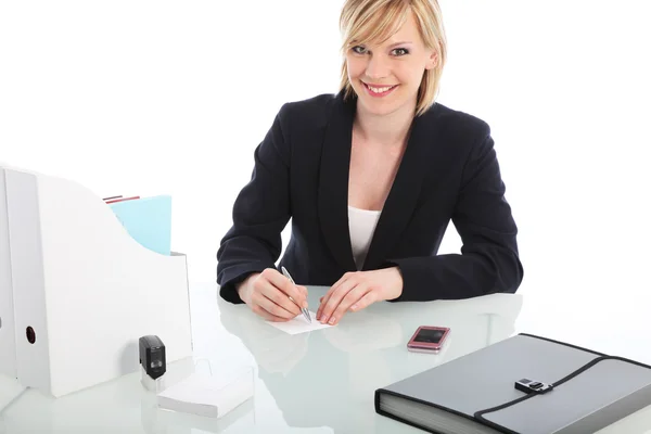 Uśmiechnięta kobieta siedzi przy biurku — Zdjęcie stockowe