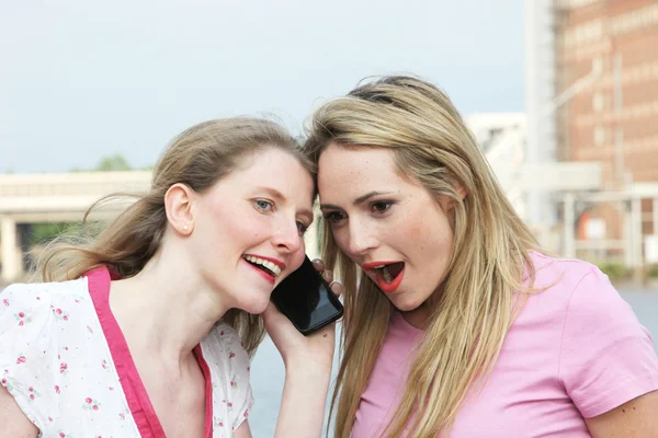 Two ladies listening to a mobile phone — Zdjęcie stockowe