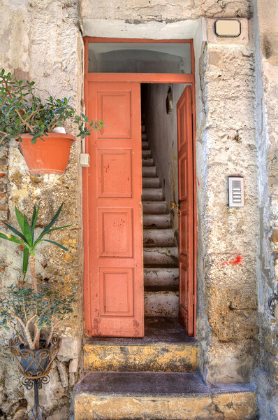 Vertical oriented image of wooden door and old narrow stairs in small house at town of Ventimiglia in Liguria, Italy.