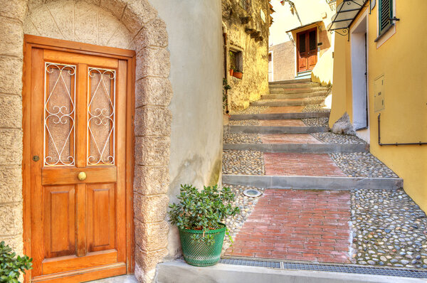 Wooden door at the entrance to small house on narrow cobbled street in town of Ventimiglia in Liguria, Italy.