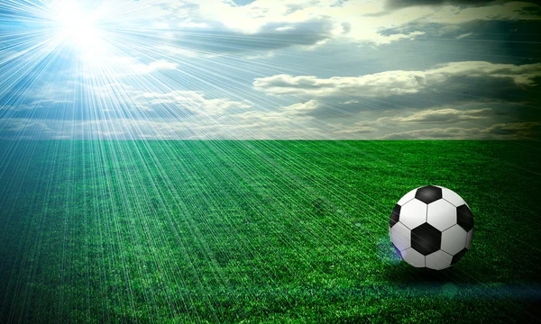 Um belo prado verde com uma bola de futebol. Tudo no céu por do sol — Fotografia de Stock