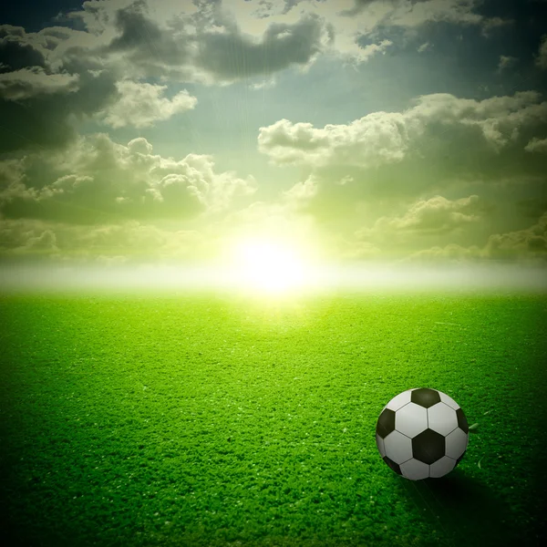 Bir futbol topu ile güzel bir yeşil çayır. Tüm gökyüzü günbatımı üzerinde — Stok fotoğraf