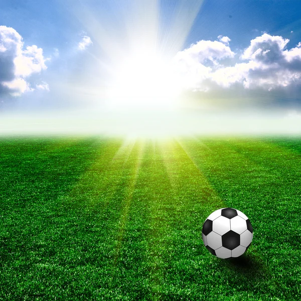 उस पर एक फुटबॉल गेंद के साथ एक अच्छा हरा घास। सभी आकाश सूर्यास्त पर — स्टॉक फ़ोटो, इमेज