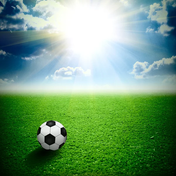उस पर एक फुटबॉल गेंद के साथ एक अच्छा हरा घास। सभी आकाश सूर्यास्त पर — स्टॉक फ़ोटो, इमेज