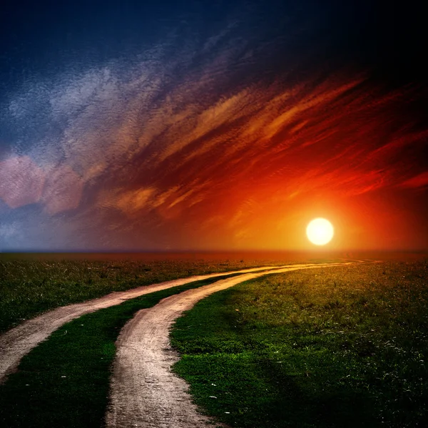 Δρόμο στο πεδίο με τα σύννεφα και το ηλιοβασίλεμα — Φωτογραφία Αρχείου