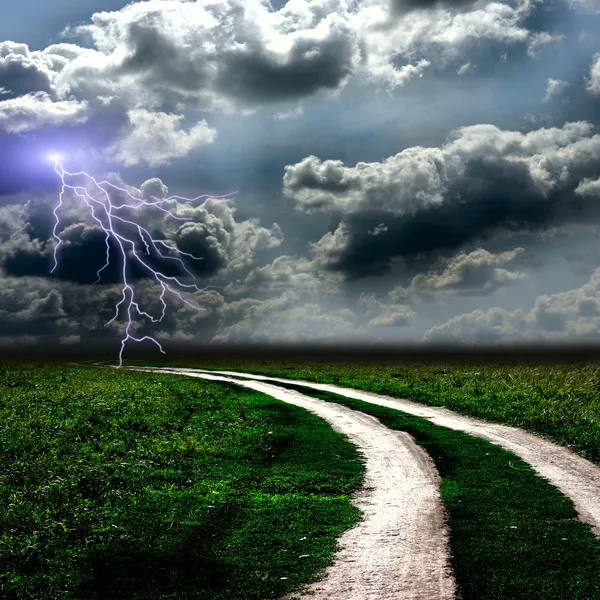Vägen genom ängen och den stormig himmel — Stockfoto