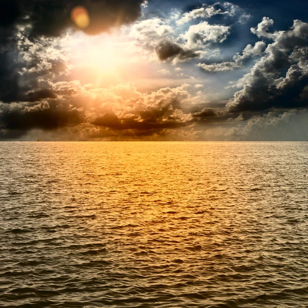 Желтое солнце заходит посреди океана — стоковое фото