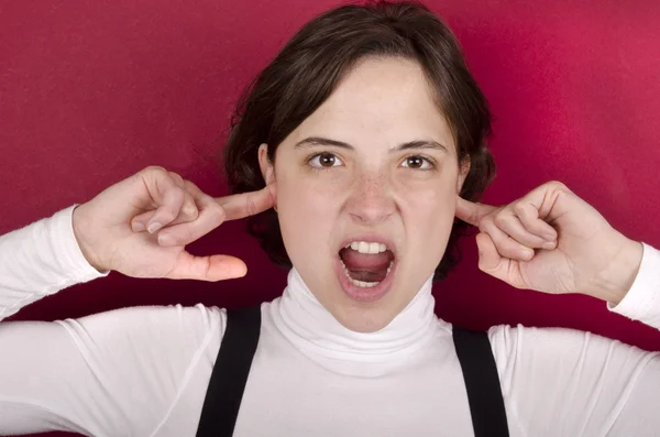 Ung kvinna skriker med fingrar i öronen — Stockfoto