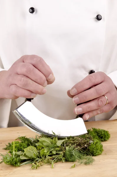 Female chef cuts fresh herbs with a herb chopper — Stock Photo, Image