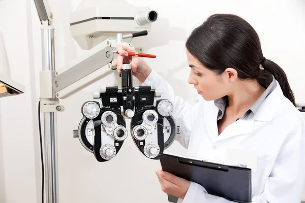 Оптометрист смотрит на фороптер — стоковое фото