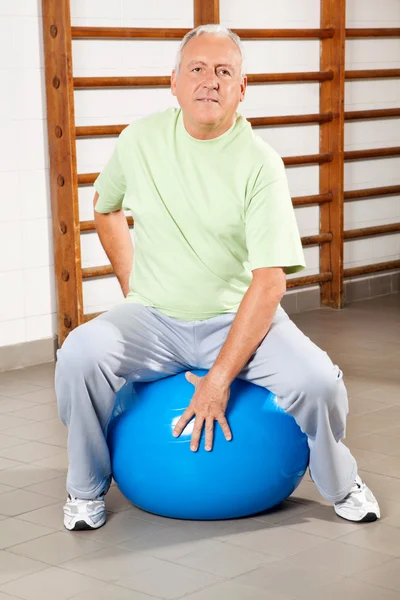 Uomo anziano seduto sulla palla fitness — Foto Stock