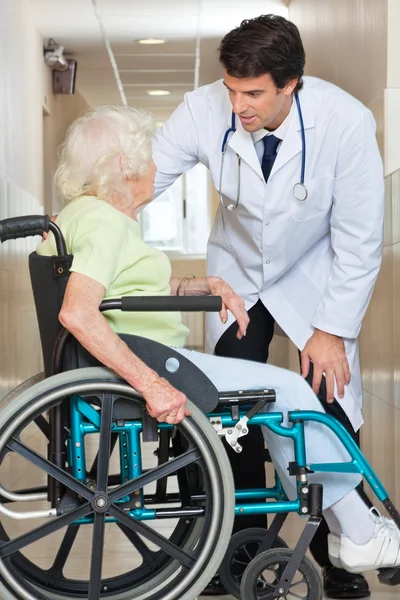 Доктор общается со старшей женщиной, сидящей в инвалидном кресле — стоковое фото