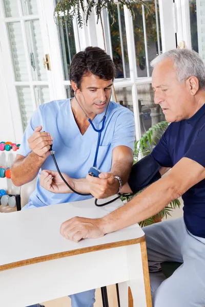 Verpleger controleren van bloeddruk van een hogere patiënt — Stockfoto