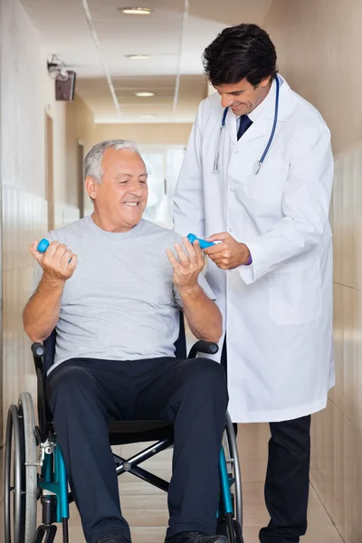 Médico dando pesos de mão para o homem sênior sentado em uma roda — Fotografia de Stock