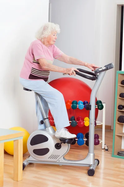 Mulher Sênior se exercitando em bicicleta — Fotografia de Stock