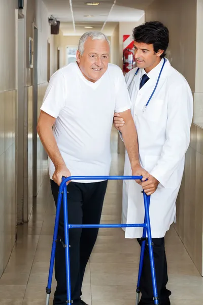 Doctor ayudando a anciano en un caminante — Foto de Stock