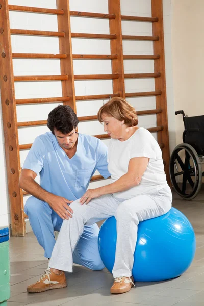 Therapeut untersucht Knie einer Seniorin — Stockfoto