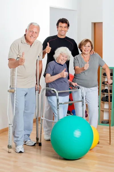 Personas mayores con discapacidad con entrenador mostrando pulgares — Foto de Stock