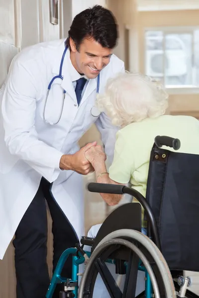 Médico asistiendo a una mujer mayor en silla de ruedas — Foto de Stock