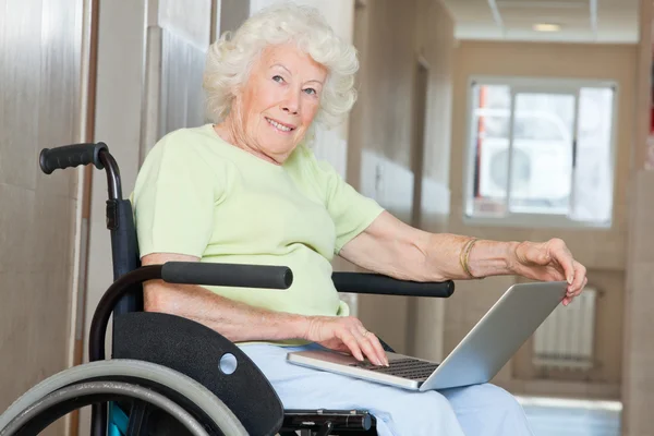 Mujer mayor en silla de ruedas usando ordenador portátil — Foto de Stock