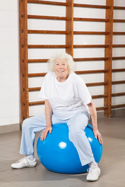 Šťastný starší žena sedící na fitness míč — Stock fotografie