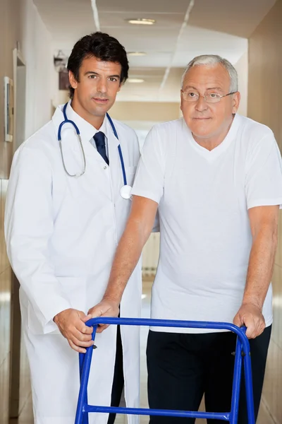 Лікар, допомагаючи старий з його Уокер — стокове фото