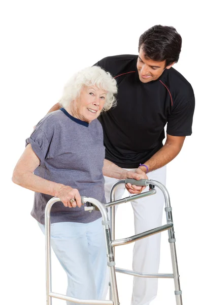 Anziana donna holding walker mentre trainer assistere il suo — Foto Stock