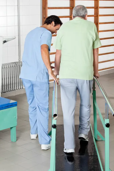 Mężczyzna terapeuta pomoc starszy mężczyzna chodzić przy wsparciu — Zdjęcie stockowe