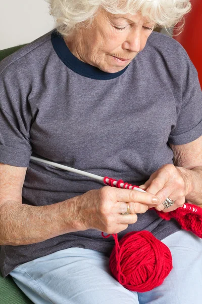 Seniorin strickt mit roter Wolle — Stockfoto