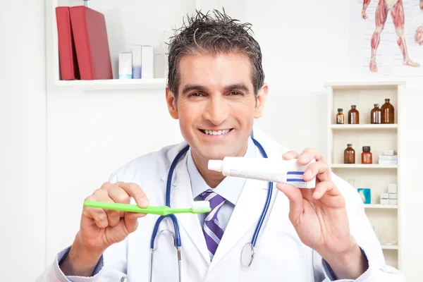 Docteur tenant brosse à dents et dentifrice — Photo