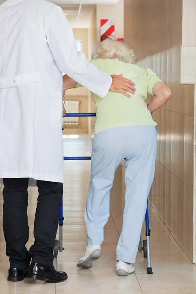 Doktor pomáhat starší žena používat chodítko — Stock fotografie