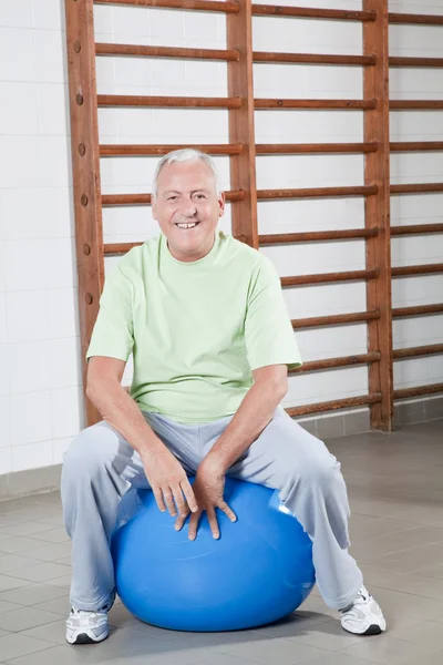 Homem sênior senta-se em um Fitball — Fotografia de Stock