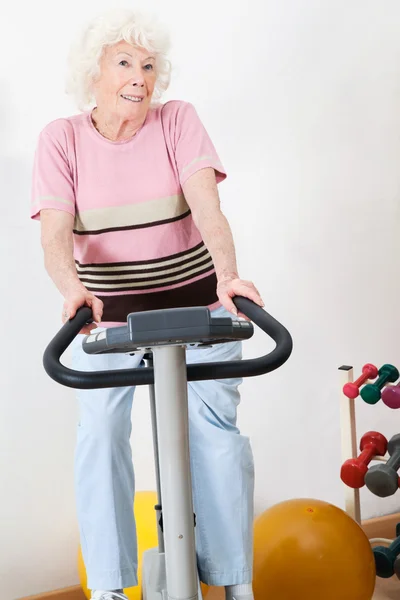 Szczęśliwa kobieta starszy ćwiczeń na rowerze — Zdjęcie stockowe