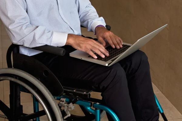 Человек на инвалидной коляске с ноутбуком — стоковое фото