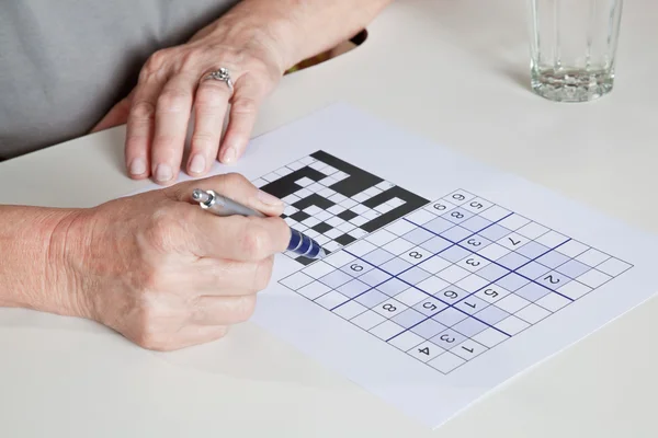 Volwassen vrouw spelen sudokupuzzel — Stockfoto