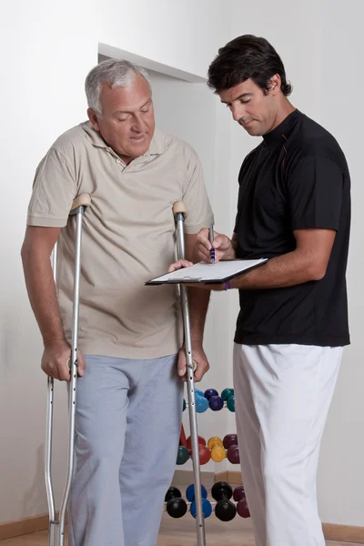 Paciente con muletas y médico — Foto de Stock